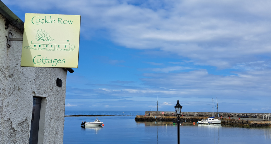 Cockle Row sign with the harbour in the background